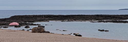 a beach with an umbrella and rocks in the water at Dialiskari Villas in Marathopolis