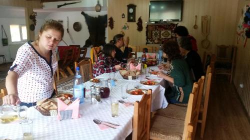 un gruppo di persone sedute a tavola che mangiano cibo di Casa de Vacanta Neagu a Gura Teghii