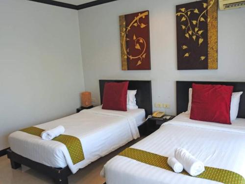 a bedroom with two beds with red and white pillows at Napalai Resort Hua Hin in Hua Hin