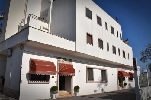 - un bâtiment blanc avec des auvents rouges dans l'établissement Hotel Joy, à Castel Volturno