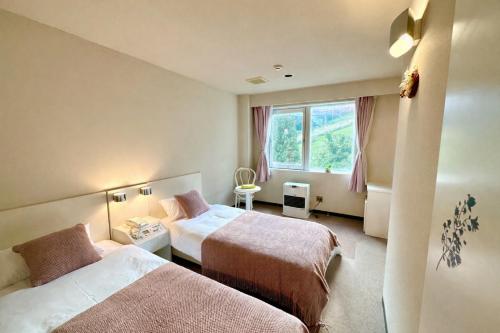 a hotel room with two beds and a window at 雪场缆车站旁 Hotel Justice-Ski IN Ski OUT-独立卫浴 in Seki