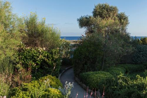 a winding path through a garden with the ocean in the background at Dialiskari Villas in Marathopolis