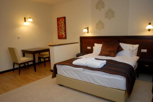 a bedroom with a bed and a table and a desk at Hotel Aurum in Hajdúszoboszló