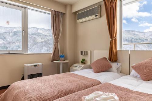 a bedroom with two beds and a large window at 雪场缆车站旁 Hotel Justice-Ski IN Ski OUT-独立卫浴 in Seki