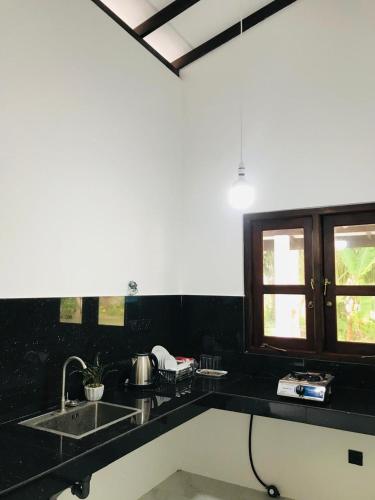 a black kitchen with two sinks and a window at The Vinza in Hikkaduwa