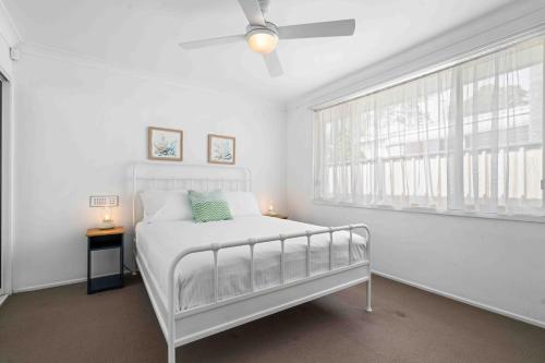 a white bedroom with a bed and a window at Casa LuCe by Experience Jervis Bay in Erowal Bay