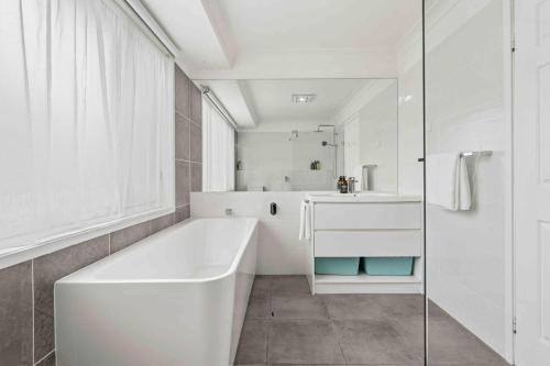 a white bathroom with a tub and a sink at Casa LuCe by Experience Jervis Bay in Erowal Bay