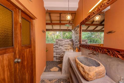 a bathroom with a large stone sink and a tub at OMA Hikkaduwa in Hikkaduwa