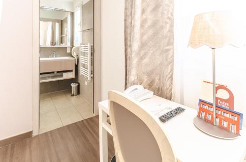 a room with a desk with a computer and a bathroom at Hôtel CASABELLA Cannes Mouans Sartoux in Mouans-Sartoux