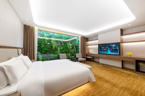 a bedroom with a white bed and a large window at Honder International Hotel in Guangzhou