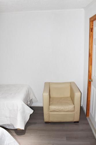 a bedroom with a chair next to a bed at Residencial Victoria Said in Linares