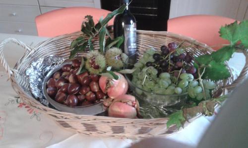 a basket of fruit on a table with a bottle of wine at Villa C&C in Lierna