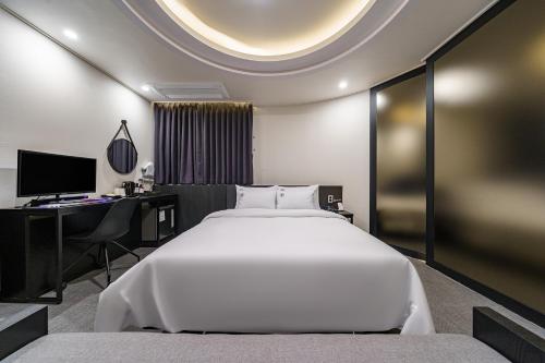 a bedroom with a large white bed and a desk at Daejeon Brown Dot Wolpyeong in Daejeon