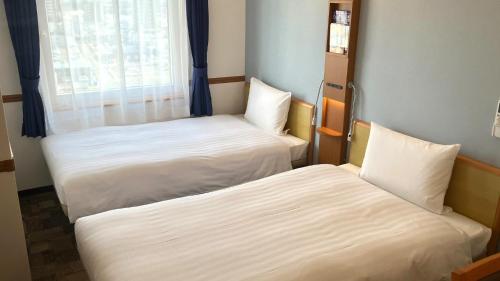two beds in a small room with a window at Toyoko Inn Shin-yamaguchi-eki Shinkansen-guchi in Yamaguchi
