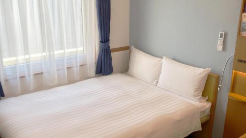 a small bed in a room with a window at Toyoko Inn Shin-yamaguchi-eki Shinkansen-guchi in Yamaguchi