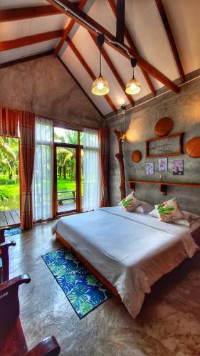 a bedroom with a large bed in a room with windows at BaanRaiChayKhaoFarmStay in Nakhon Si Thammarat