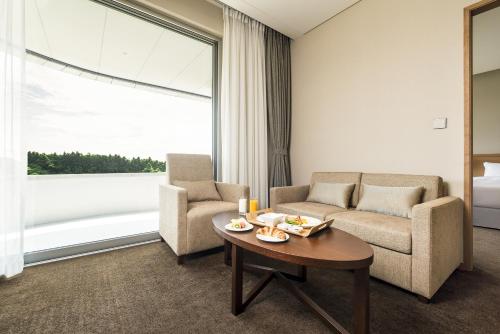 a living room with a couch and two chairs and a table at Hidden Cliff Hotel and Nature in Seogwipo