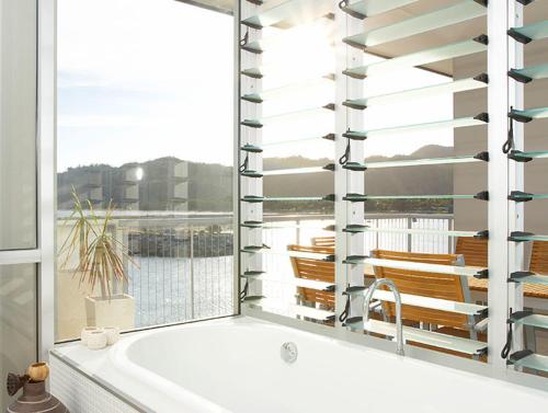 a bath tub in a bathroom with a window at Grand Mercure Apartments Magnetic Island in Nelly Bay