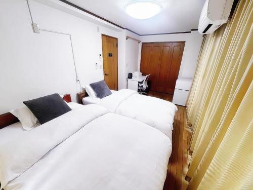 a bedroom with two beds with white sheets at 烟雨轩 203 in Tokyo