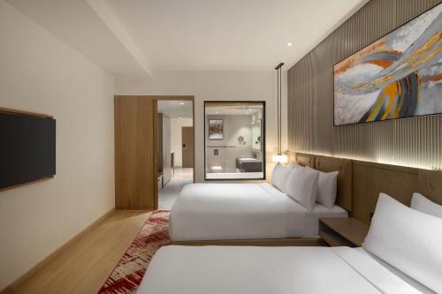 a hotel room with two beds and a television at Ramada by Wyndham Sonipat Murthal in Sonīpat