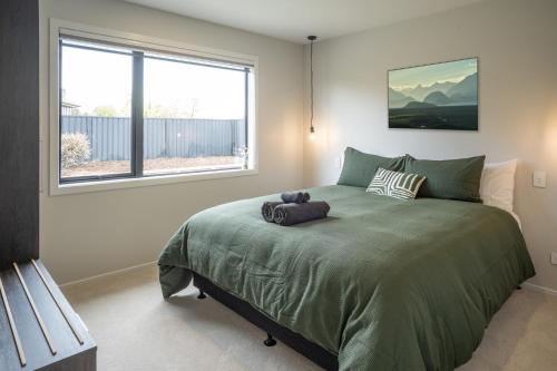 a bedroom with a large bed with a window at Murchison View house with Jacuzzi in Te Anau