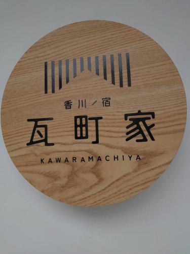 a round wooden sign with a kanbarayrinth sqor on it at 瓦町家kawaramachiya in Takamatsu
