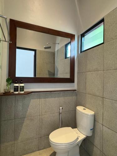 a bathroom with a toilet and a mirror at Wish Uluwatu in Uluwatu