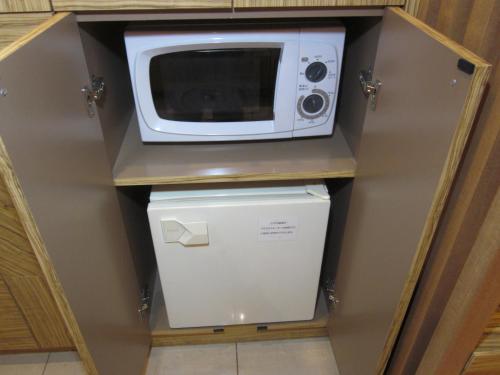 a microwave sitting on top of a refrigerator at Hotel Aura Daito (Adult Only) in Daitō