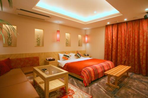 a hotel room with a bed and a couch at Hotel Aura Daito (Adult Only) in Daitō