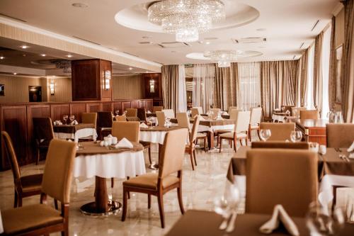 a restaurant with tables and chairs in a room at Ramada by Wyndham Almaty in Almaty