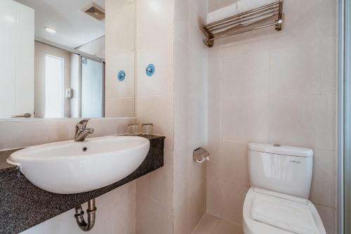 a white bathroom with a sink and a toilet at Ascent Premiere Hotel and Convention in Malang