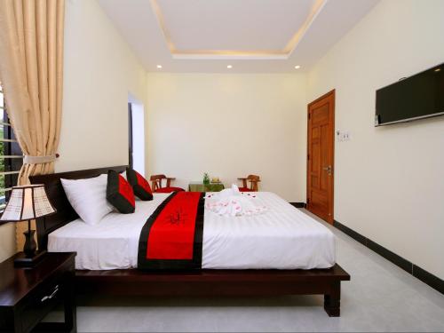 a bedroom with a large bed with a tv on the wall at Fireworks Homestay in Hoi An