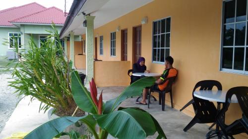 two people sitting at tables outside of a building at Tokman Inn in Pantai Cenang