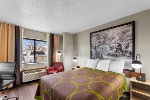 a hotel room with a bed and a chair and a window at Super 8 by Wyndham Evansville East in Evansville