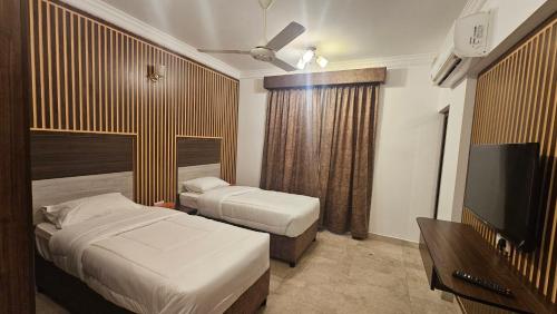 a hotel room with two beds and a flat screen tv at بيان للاجنحة الفندقية - سوق الخوير in Muscat