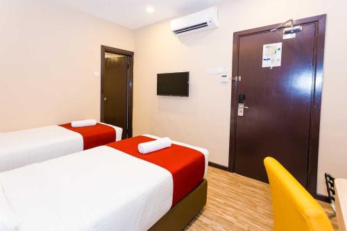 a room with two beds and a door and a chair at Icon Hotel Segamat in Segamat