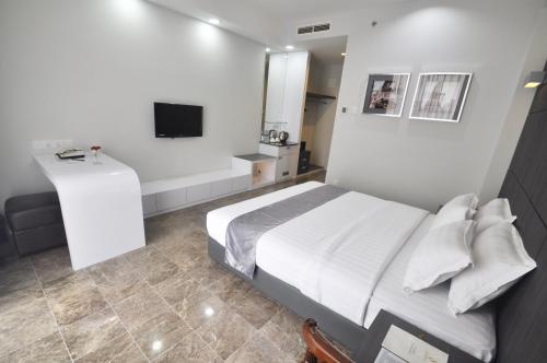 a bedroom with a white bed and a television at Dreamtel Jakarta in Jakarta
