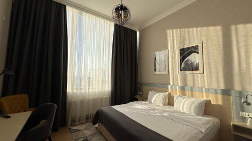 a bedroom with a bed and a desk and a window at Navruz Hotel Tashkent in Tashkent