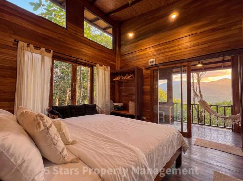 a bedroom with a bed in a room with windows at Epic Views Cabins - Ocean or Mountains, your choice in Ko Phangan