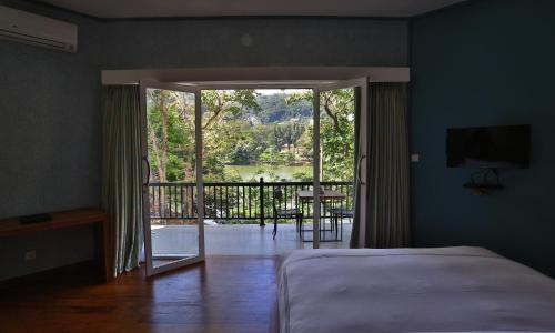 a bedroom with a bed and a view of a balcony at Viyana Boutique Hotel in Kandy