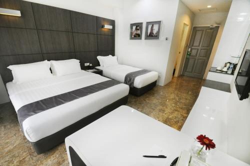a hotel room with two beds and two tables at Dreamtel Jakarta in Jakarta