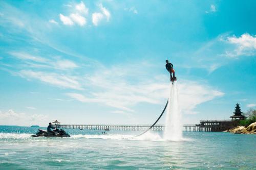 a man is standing on top of the water at Turi Beach Resort in Nongsa