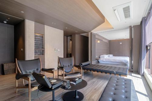 a room with chairs and a bed in the background at The Moor Wellnsee Pool Villa in Busan