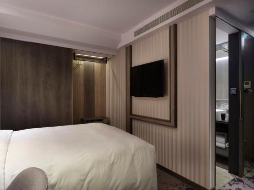 a bedroom with a bed and a tv on a wall at At Home Hotel Ximen in Taipei