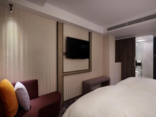 a hotel room with a bed and a tv at At Home Hotel Ximen in Taipei