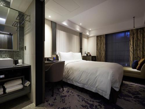 a hotel room with a large bed and a desk at At Home Hotel Ximen in Taipei