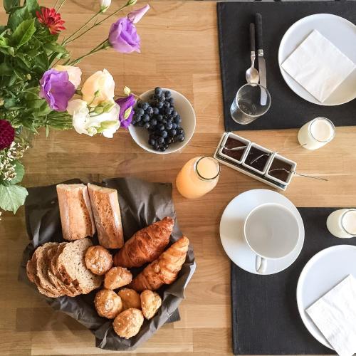 een tafel met een bord brood en gebak bij Maison d'Hôtes Les Petites Terres in Sainte-Marie-de-Ré