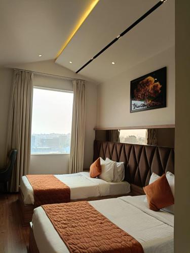 a hotel room with two beds and a window at The Pearl Petal in Rohtak
