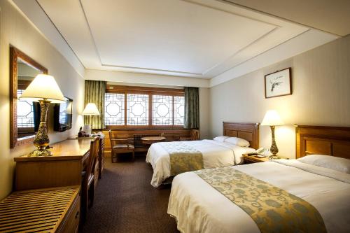 Habitación de hotel con 2 camas y escritorio en Commodore Hotel Busan, en Busan