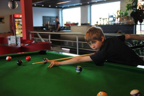 a young boy playing pool on a pool table at Hotel Zebetinsky Dvur Brno in Brno